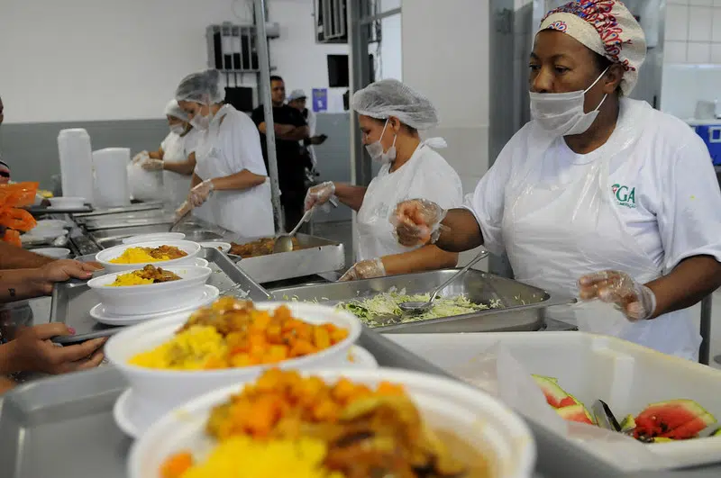 Profissionais servindo refeição em cozinha comunitária de Brasília